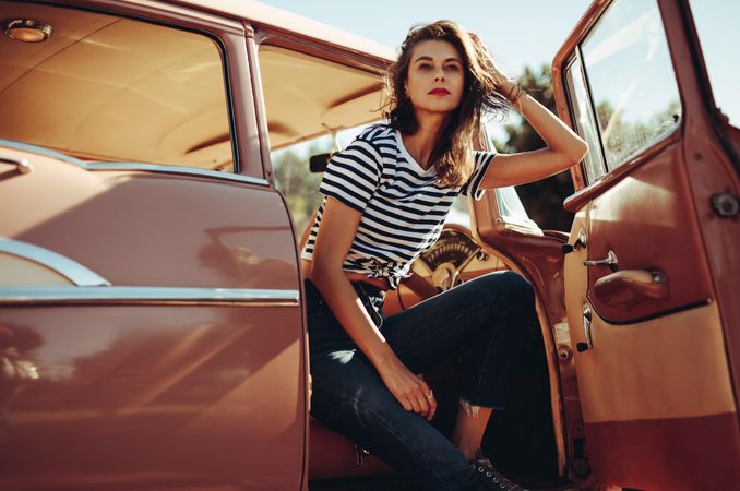 Beautiful young woman sitting in a vintage car