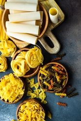 Variety of bowls of dry Italian pasta on counter with copy space