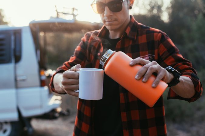 Male pouring a mug of coffee outside