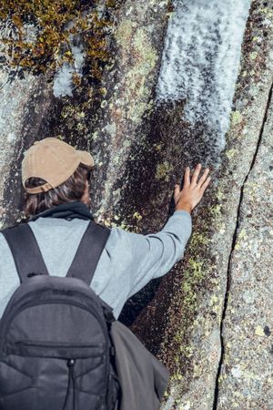 Man touching stone near trees in winter