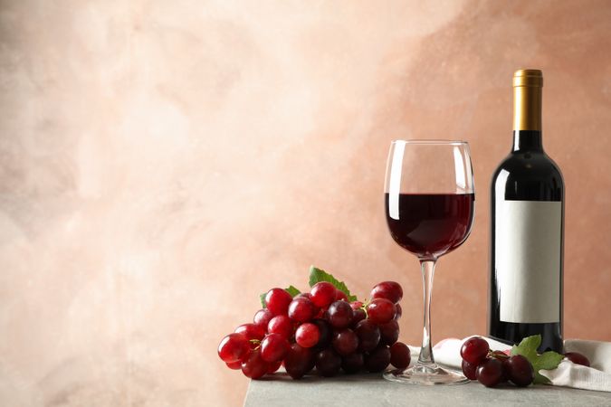 Grape, bottle and glass with wine on grey background, space for text