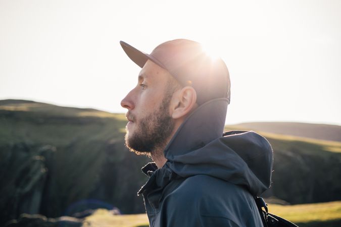 Profile of man by rugged terrain backlit by sun