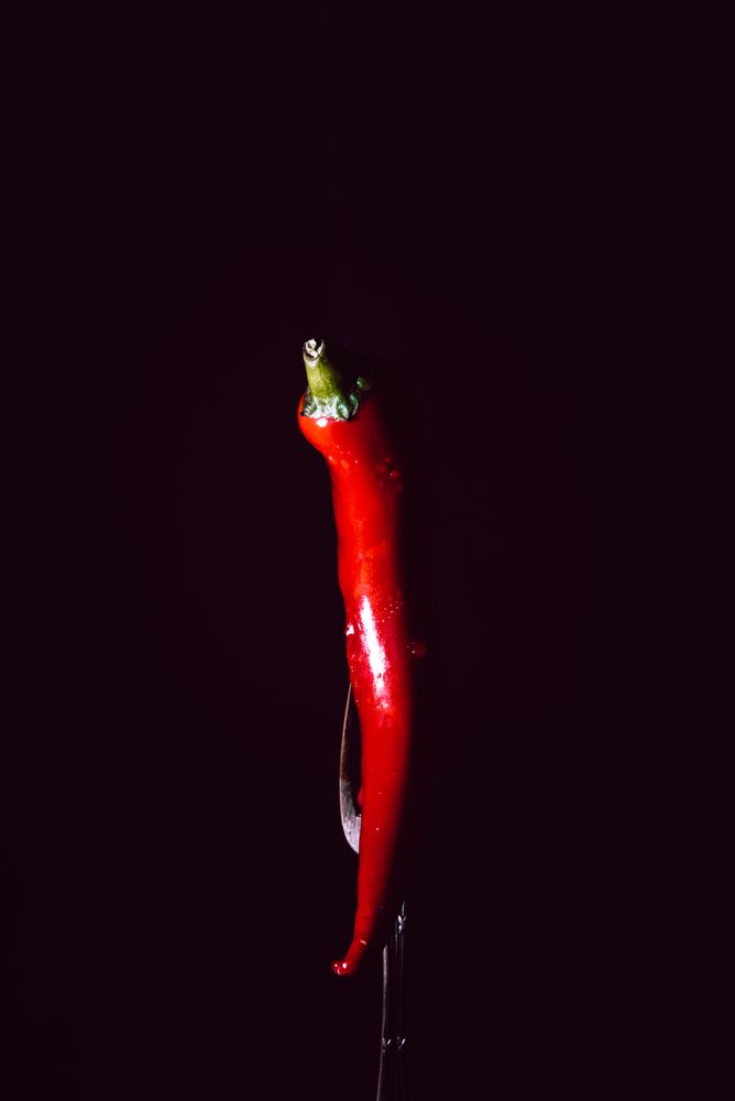 red chili pepper in fork on a dark background with smoke