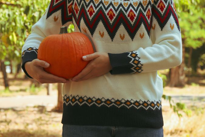 Woman in sweater and jeans hold pumpkin outdoor