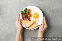 Hands reaching for breakfast plate on grey table 0PRqv4