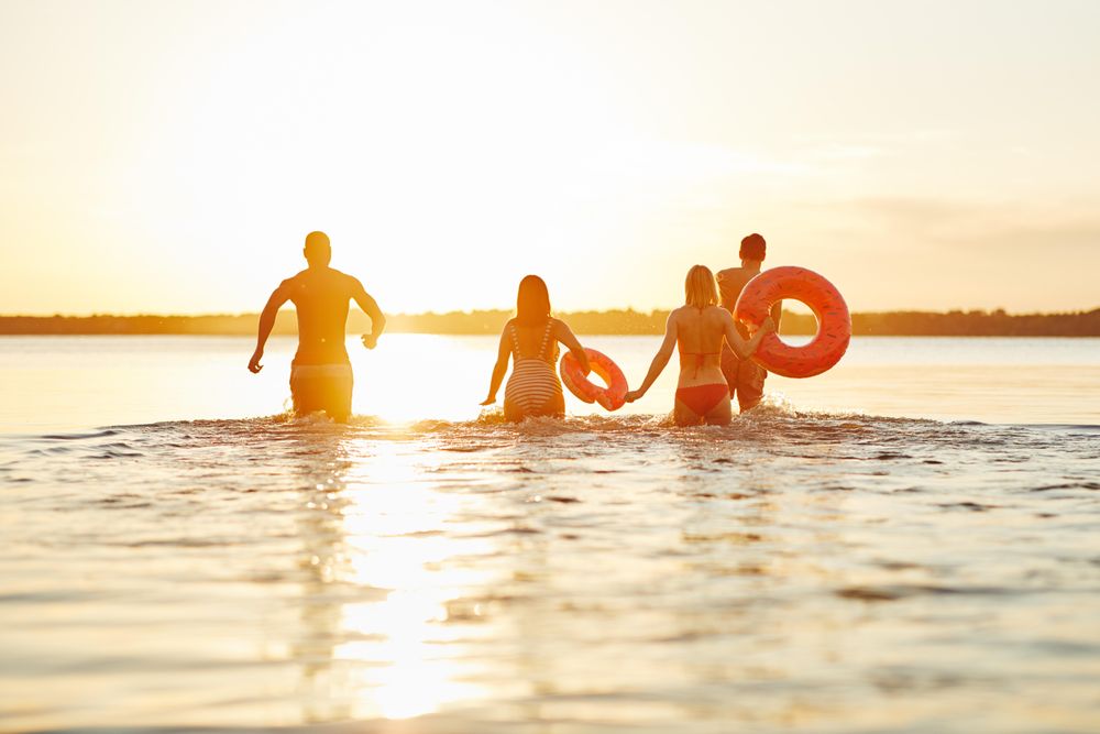 Multi-ethnic group of friends wadding through the water in swimsuits