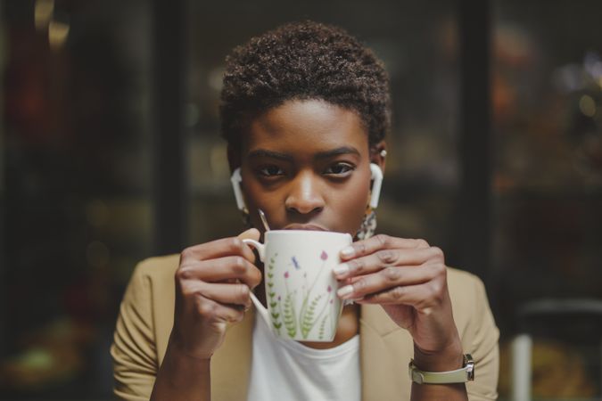 Black woman with cup of drink sitting at table in cafe
