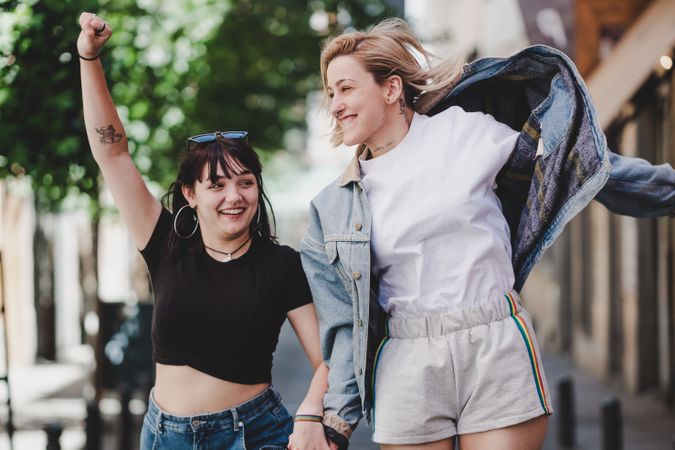 Lesbian couple with LGBT flag walking on street