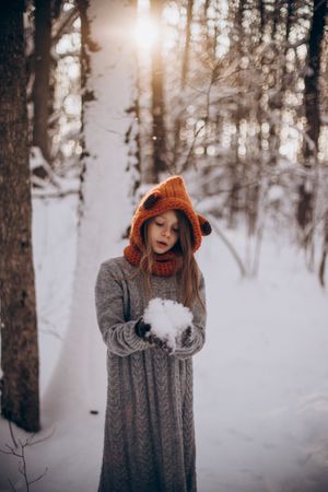 Girl holding snowball in forest