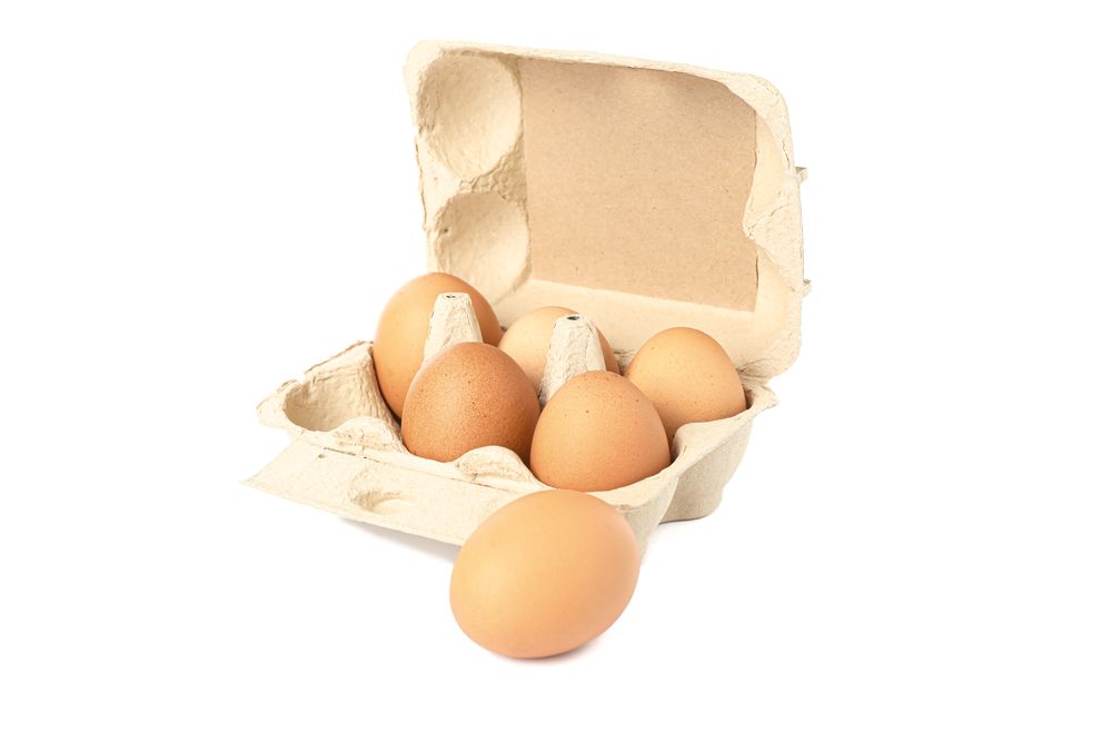 Brown chicken eggs in carton box isolated on light background