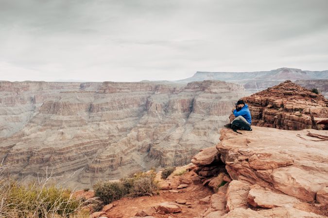 Male having rest on edge of rock and relishing beverage