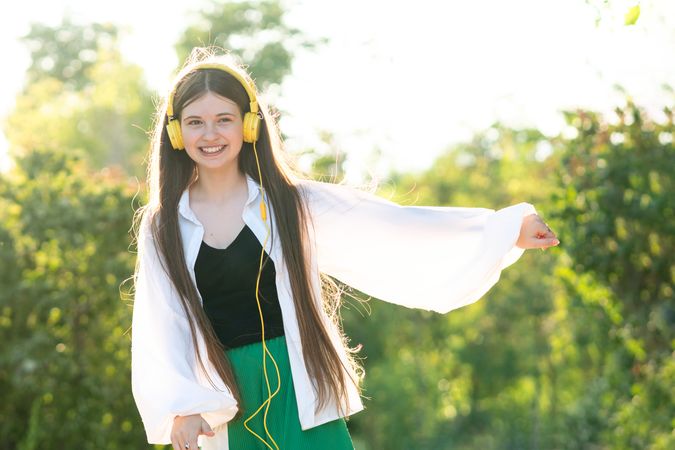 Teenage girl listening to music and dancing with headphones outdoors