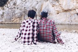 Positive woman and man resting on stone shore near river
