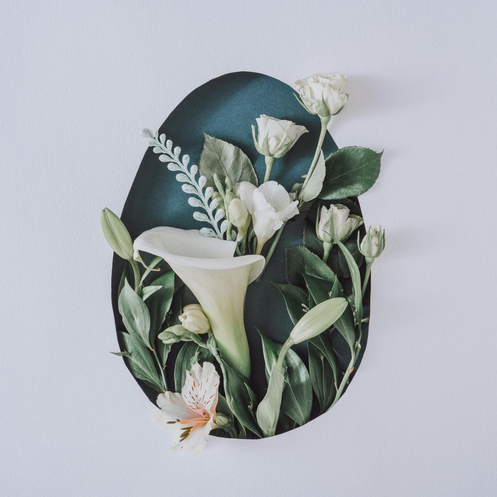 Easter layout with flowers and leaves in egg shape on light paper background