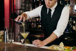 Barman working mixing pouring drink in a glass