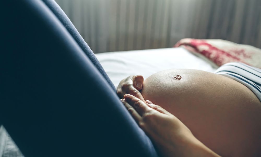 Pregnant lying touching her belly