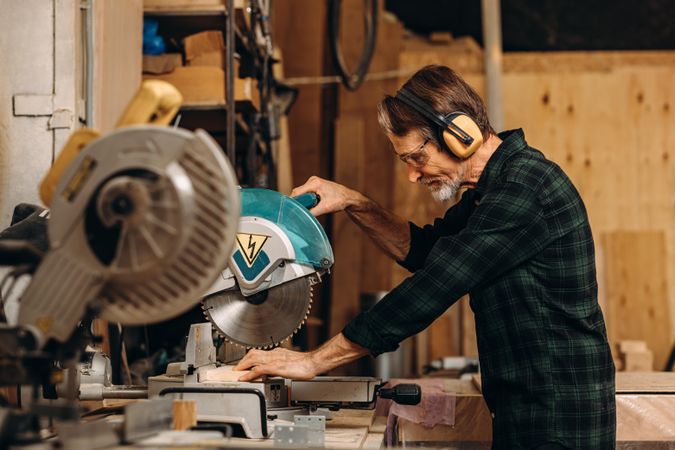 Man wearing ear protection using electric saw