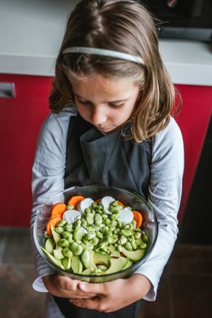 Girl with vegetable salad in kitchen