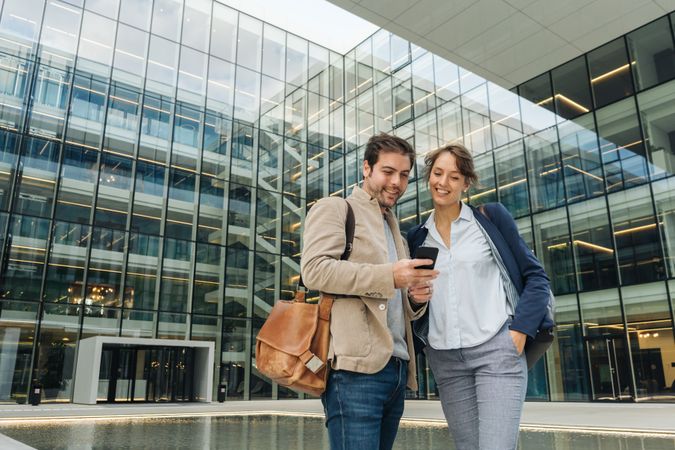 Cheerful colleagues using mobile phone after work