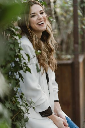 Woman sitting on planter in garden