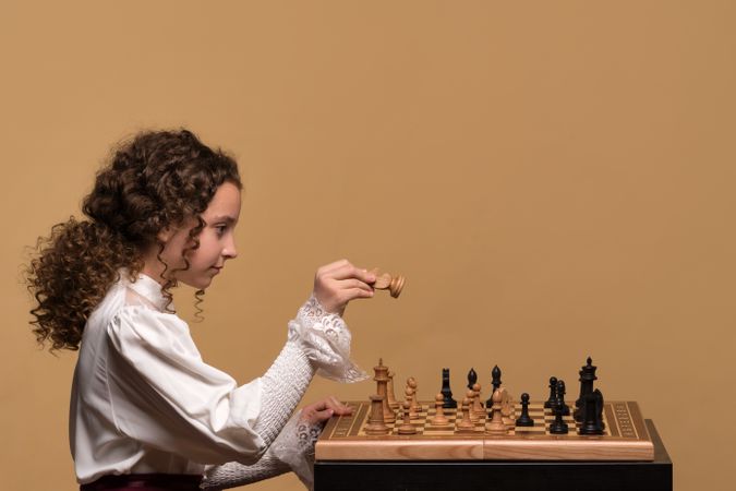 Young girl focused on moving chess piece during gameplay.