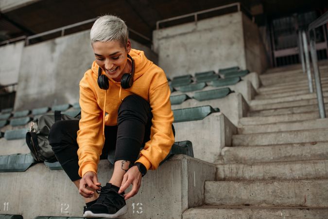 Woman runner sitting in a stadium and wearing shoes