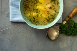 Top view of bowl of healthy chicken soup on grey kitchen counter