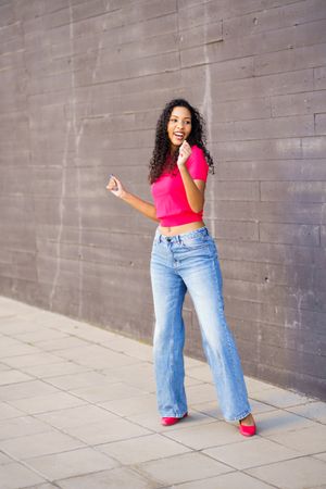 A Joyful Woman is Dancing Enthusiastically in an Urban Setting, Showcasing a Trendy Outfit