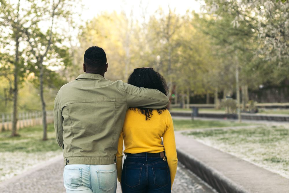 back view of a Black couple walking in a park