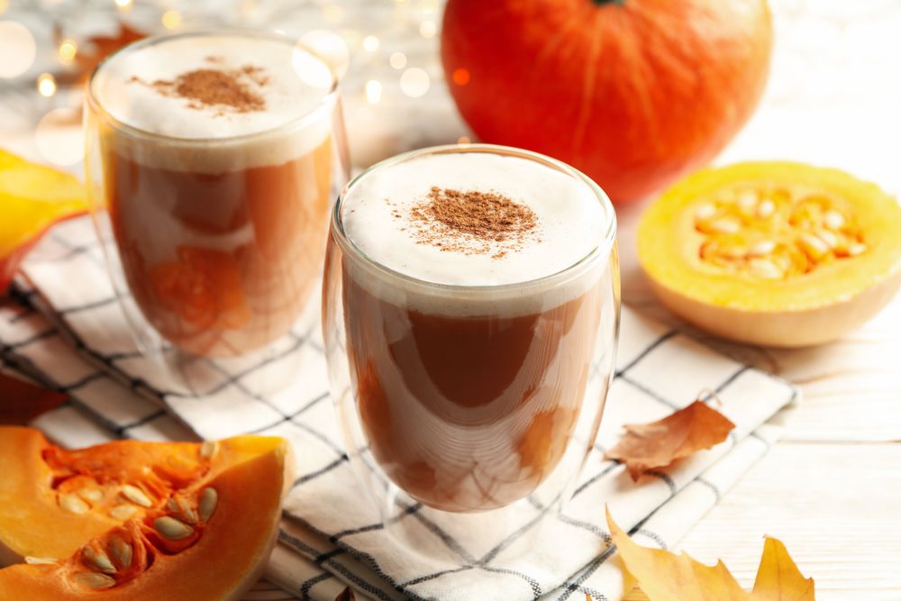 Composition with pumpkin latte on neutral wooden table