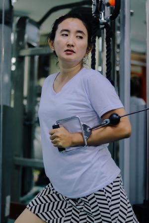 A woman uses a cable machine inside a fitness center