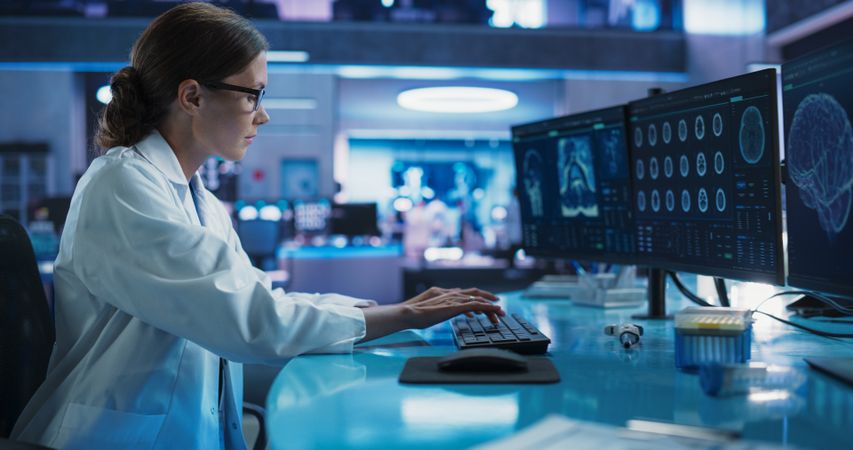 Hospital Research Laboratory: Female Medical Scientist Using Computer with Brain Scan MRI Images.
