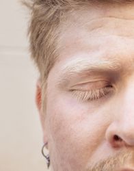 Close up portrait of a Latino man with albinism with closed eyes