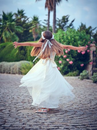 Anonymous girl in dress spinning around in park