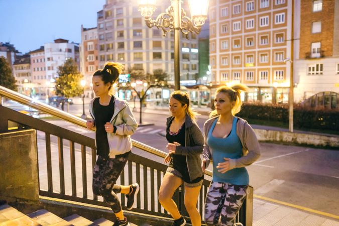 Fit women training by running up stairs in city at night