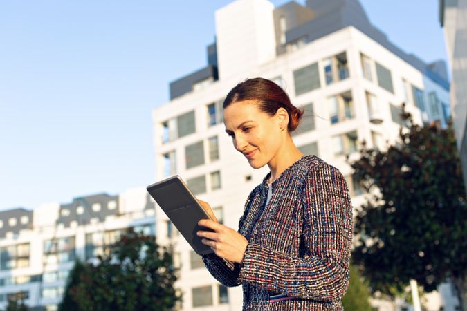 Confident entrepreneur with tablet on city street