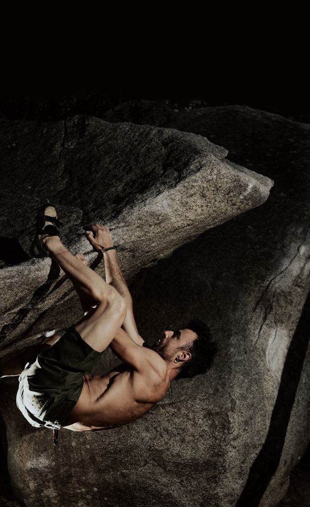 Man practicing rock climbing among large rocks in a forest