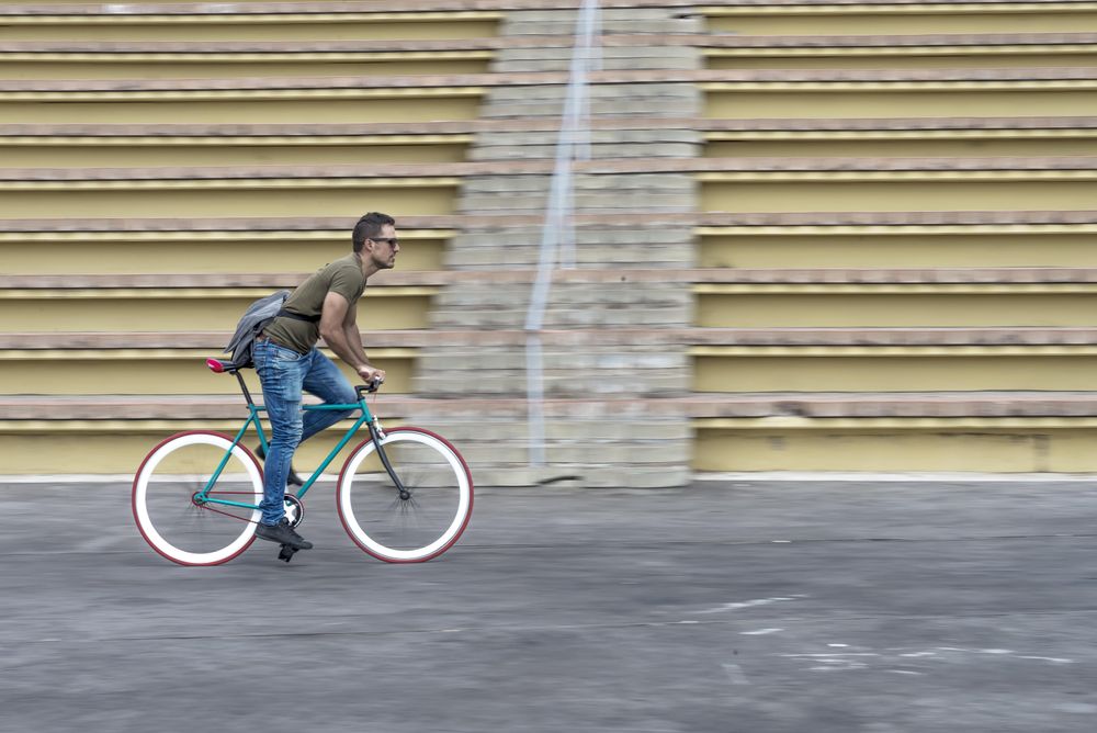 Male on colorful bike with outdoor seating in background