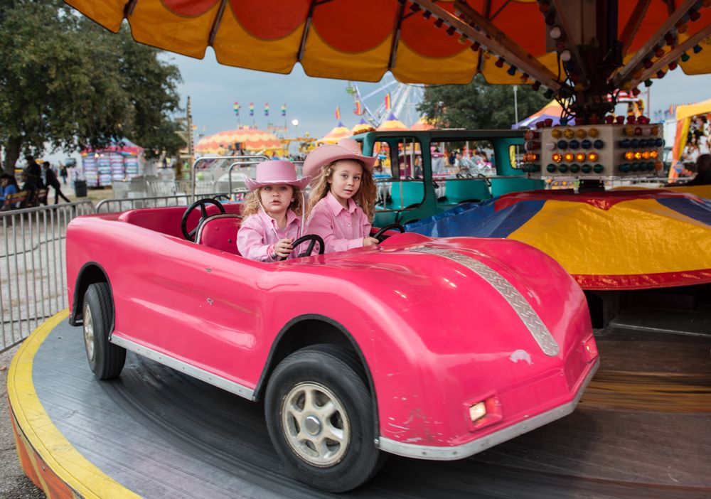 Two girls in pink cowgirl attire on carousel at Rodeo Austin, Austin, Texas