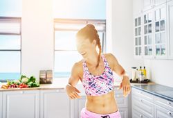 Smiling fit woman in sports gear in bright kitchen