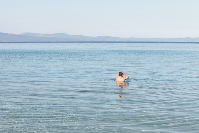 Man swimming in clear water in sunlight