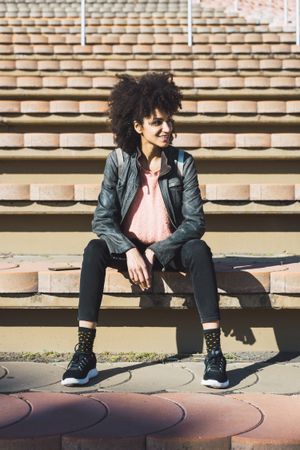 Woman with afro hair sitting on the steps of a stadium