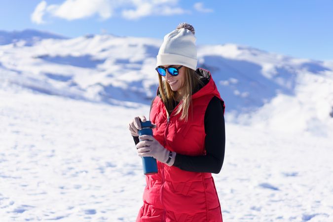 Woman in red snowsuit with water bottle on snowy mountain