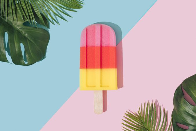 Ice cream popsicle in pastel pink on paper duotone background with tropical palm leaves