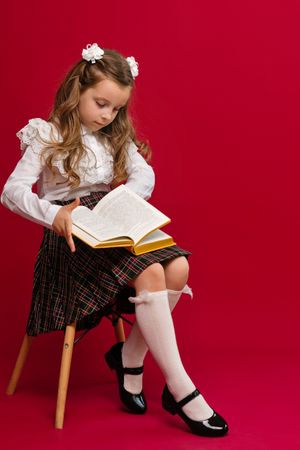 Full-length portrait preteen schoolgirl on vivid red colored background