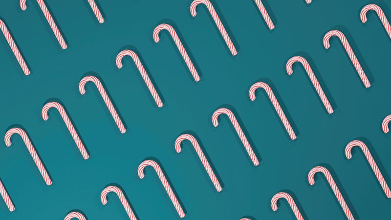 Rows of sweet candy canes with red stripes on blue background