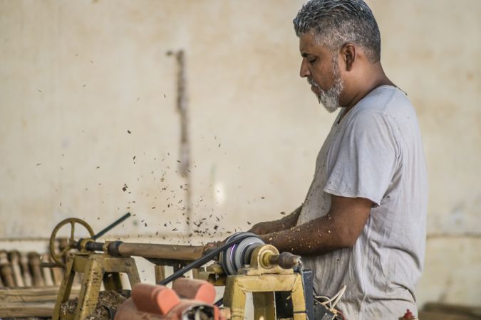 Man making detail and using woodworking machine at workplace
