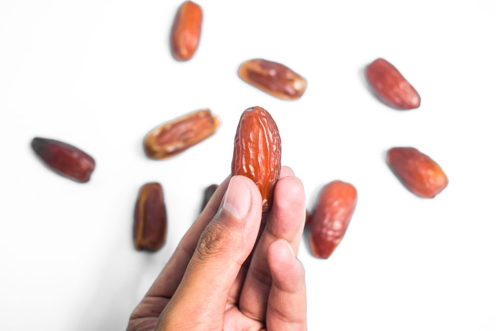 Hand hold date fruit on blank background with random dates