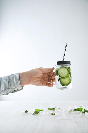 Hand holding infused cucumber mint water