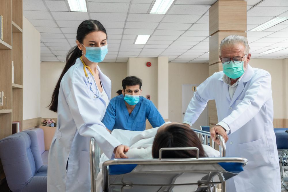 Professional medical staff wheeling patient in bed through hospital